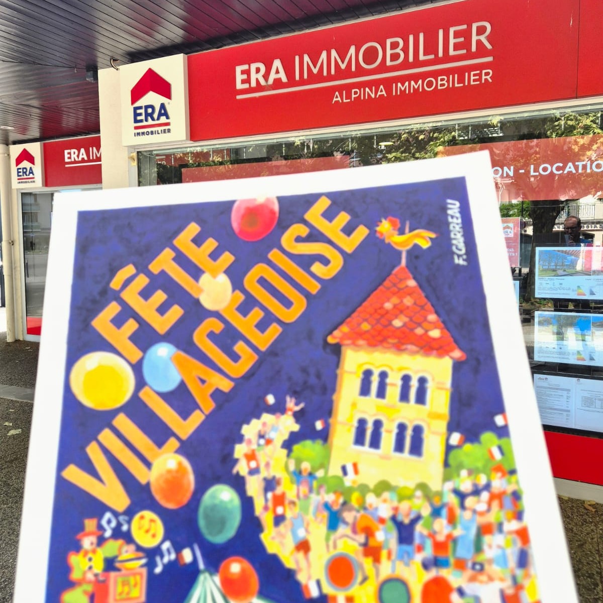 L'affiche 2026 de la F&ecirc;te Villageoise devant l'agence ERA Alpina Immobilier
