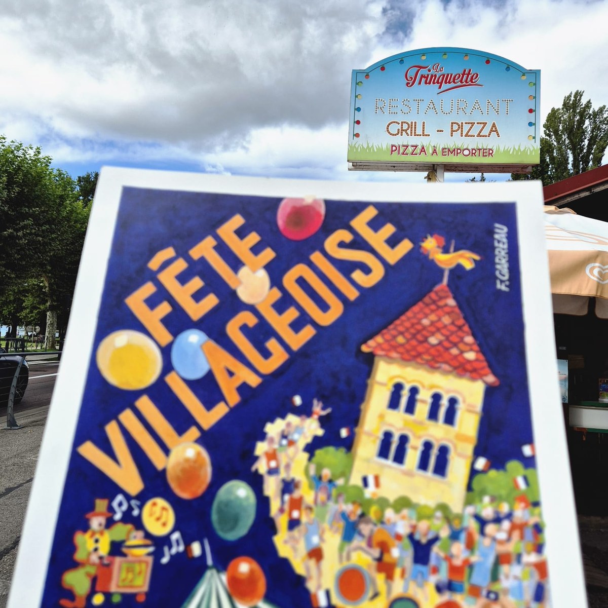 L'affiche 2026 de la Fête Villageoise devant l'enseigne de La Trinquette